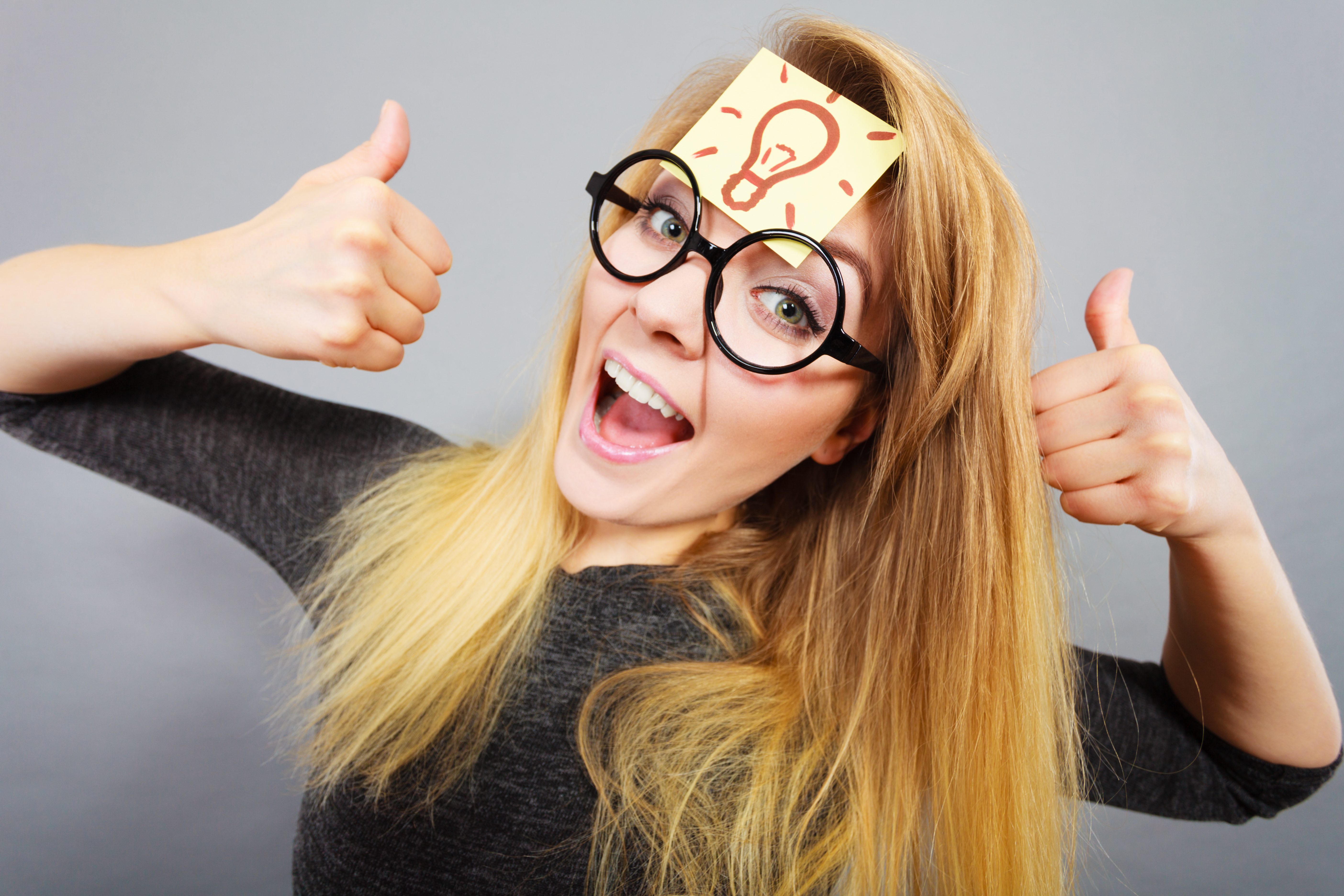 Woman with Post It note on forehead, giving thumbs up