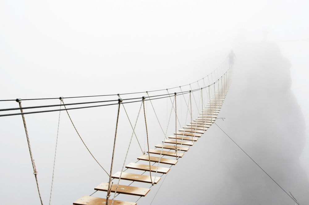 Fuzzy man walking on hanging bridge vanishing in fog