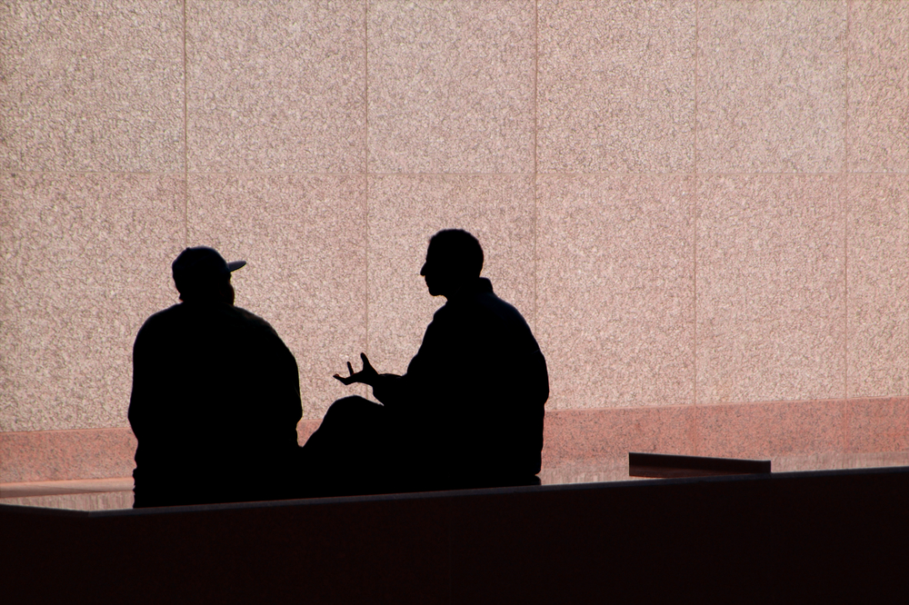 Two men talking and they are silhouetted