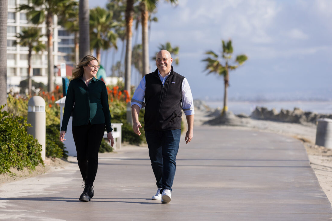 I am taking a leisurely walk on the beach with my colleagues. We are enjoying each other's company in this beautiful setting. The weather is perfect, and the scenery is breathtaking.